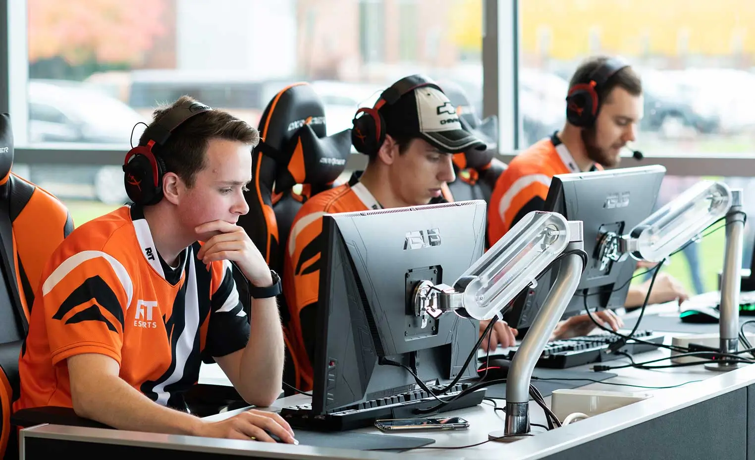 Three members of an RIT Esports team sitting in front of monitors, playing a game.