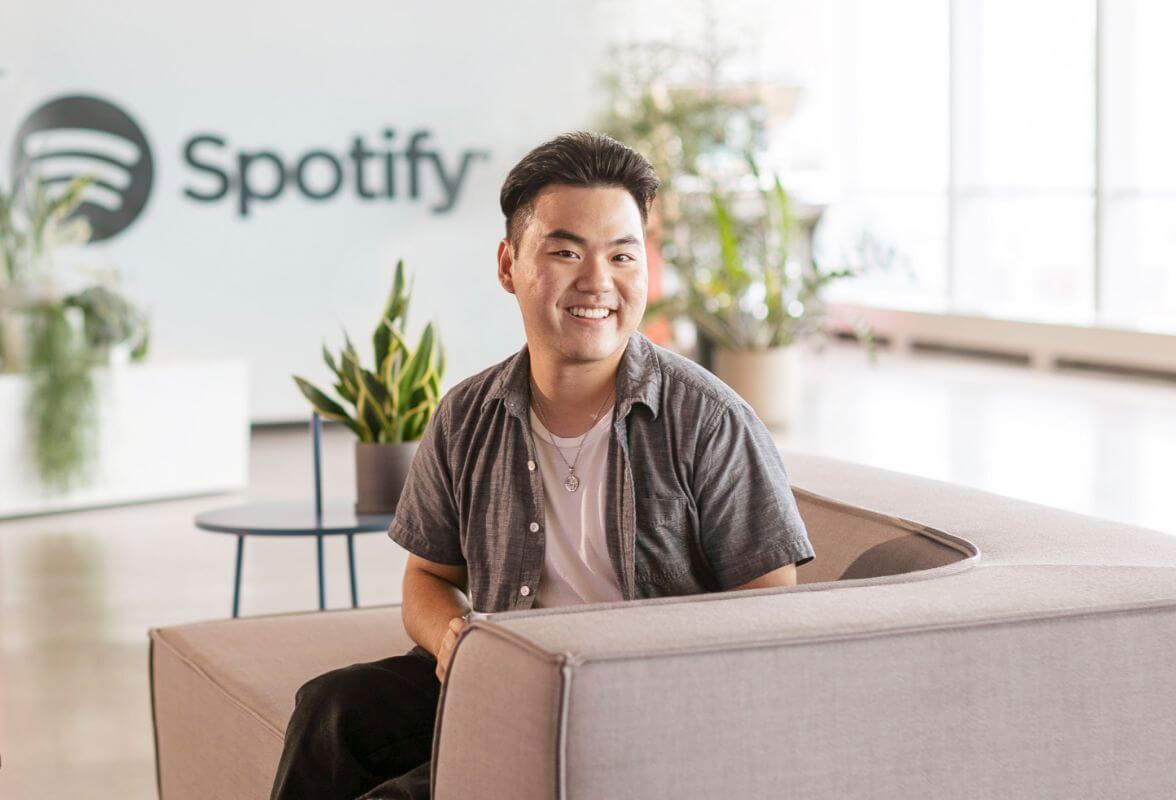An R I T student sitting on a couch in front of a Spotify sign