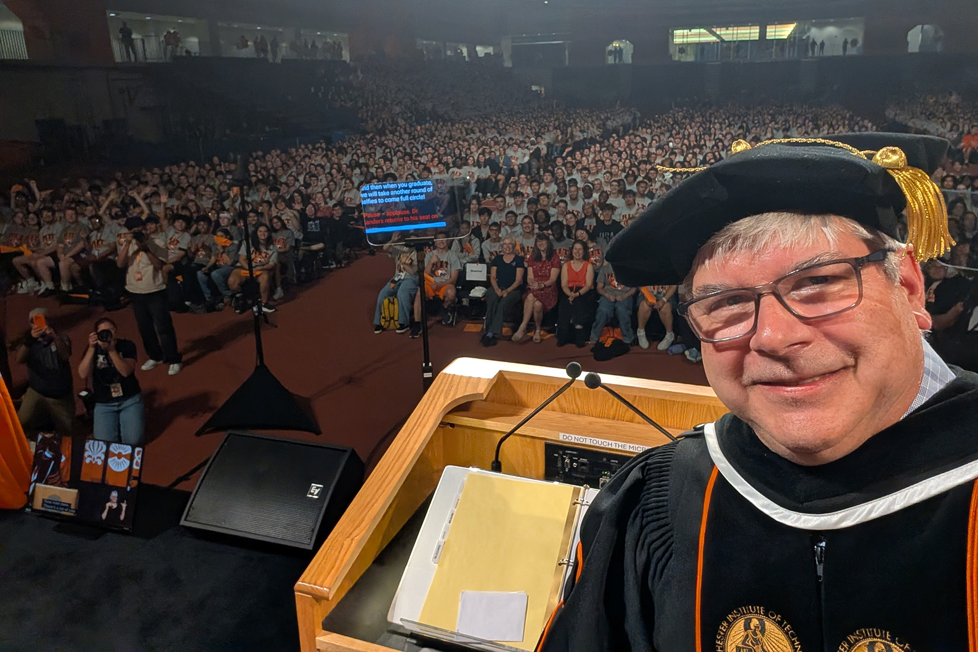 President Sanders posing for a selfie while giving a speach to the new students of the 2026 incoming class.