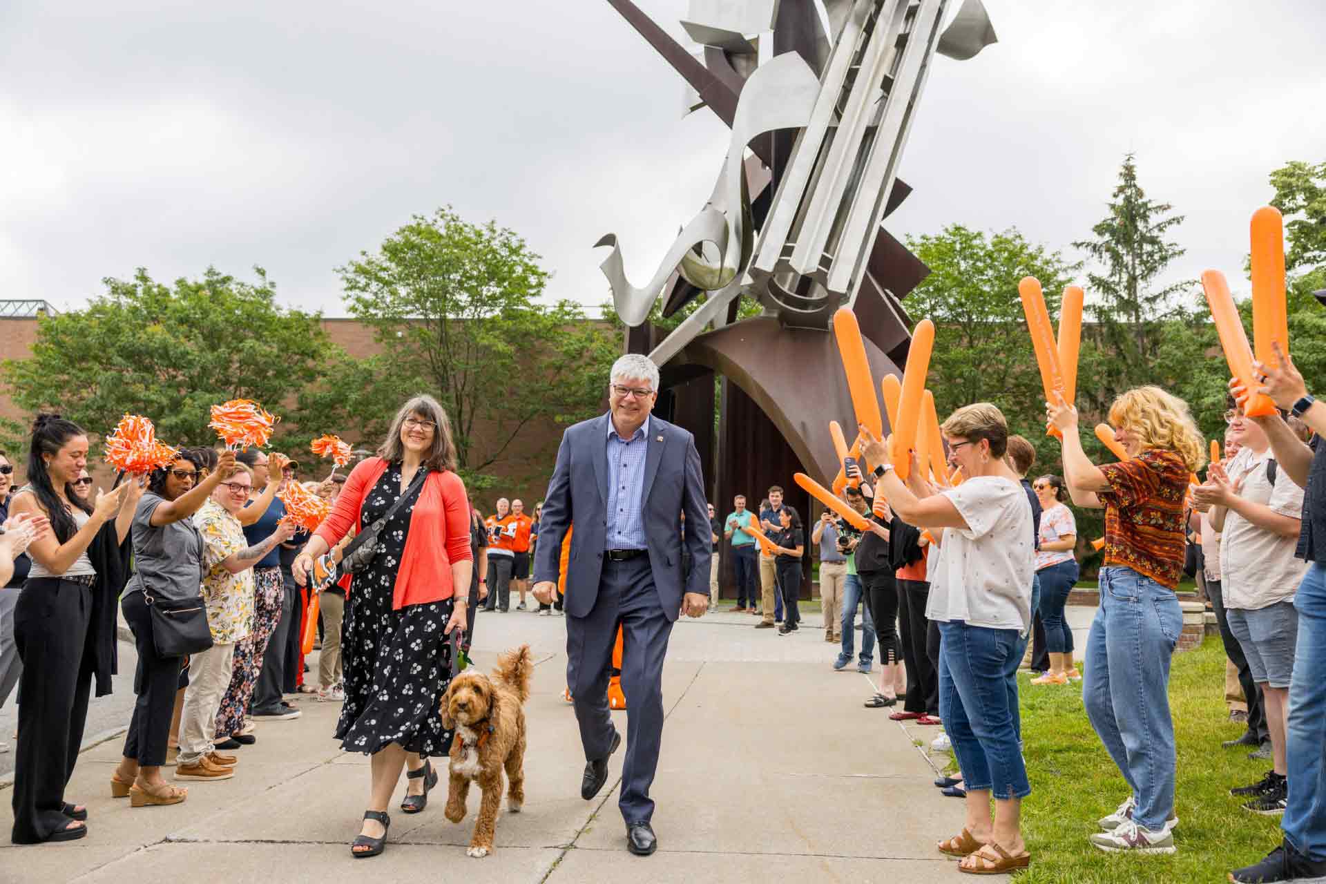 President Sanders walks along a pathway flanked by RIT community members