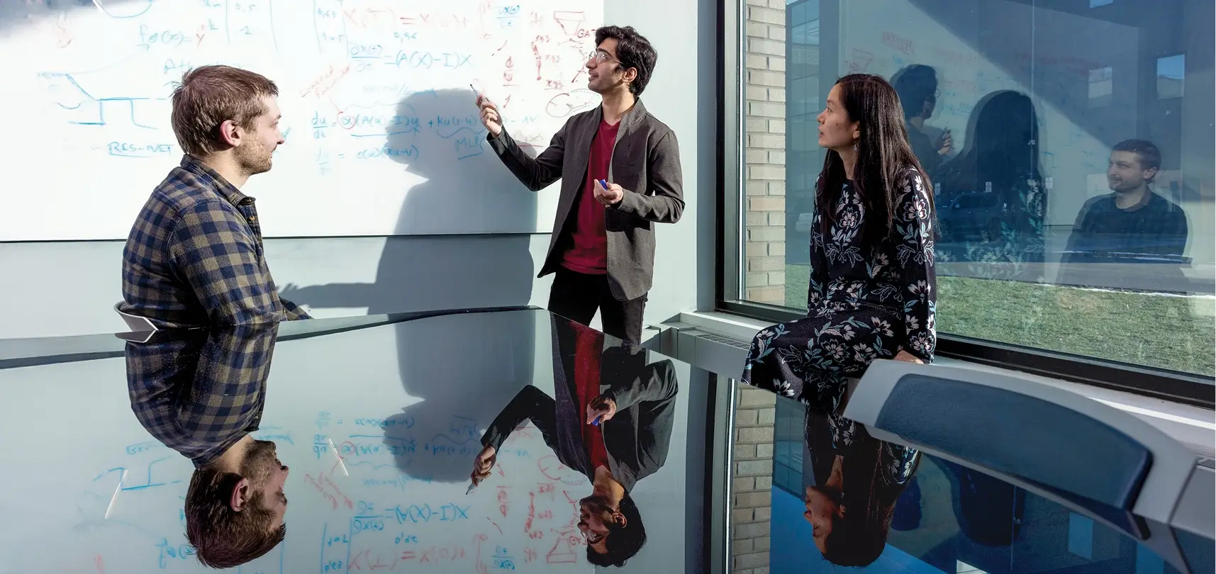 Ph.D. students Casey Meisenzahl (left), and Sumeet Atul Vadhavkar (middle), show their work to Professor Linwei Wang (right).
