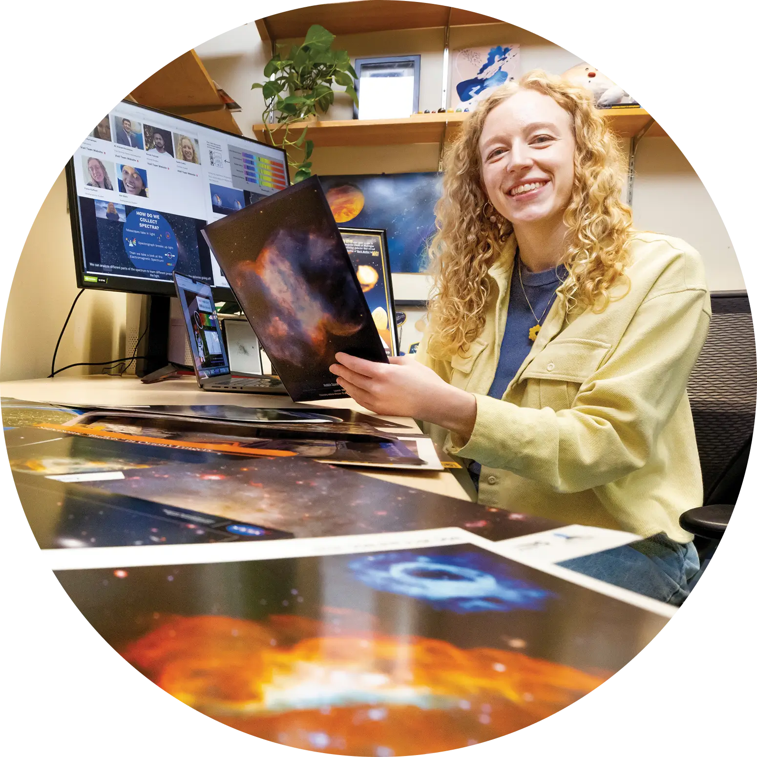Ph.D. student Sadie Coffin holding an image of a galaxy while smiling into the camera.