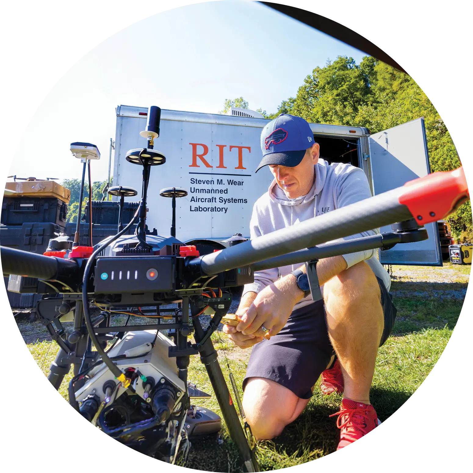 Research engineer Timothy Bauch kneeling on the ground, working on a drone.