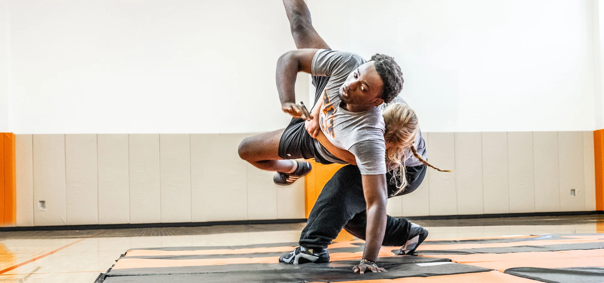 Two wrestlers grappling on a mat performing a takedown