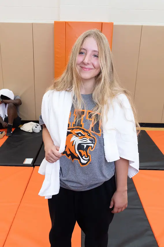 Emily Flückiger standing with a towel on her shoulders in a wrestling gym.