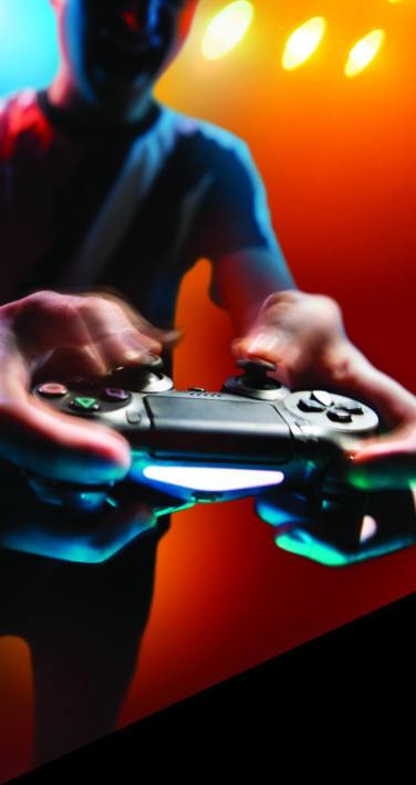 Sam Burgonye holding a playstation controller out in front of him with his fingers on the joysticks