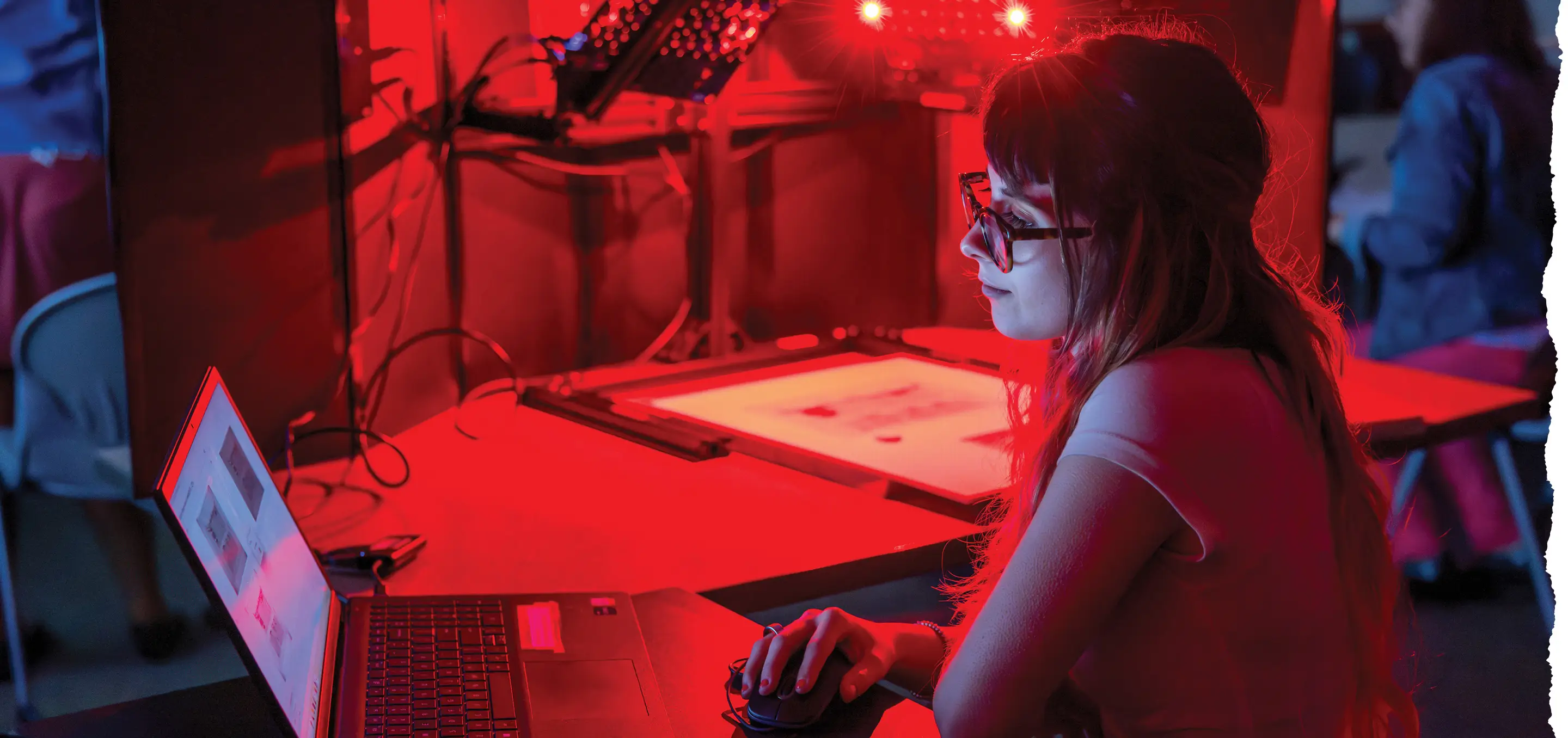 Bella Paniccia looking at the results of a scan on a laptop while red lights illuminate the document and room.
