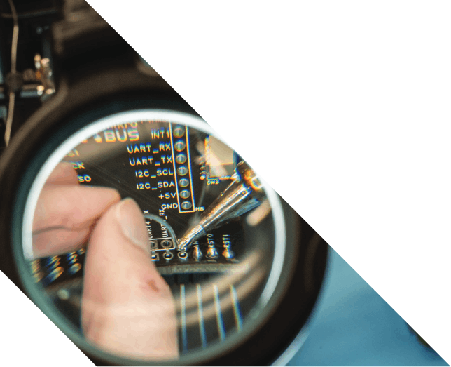 Someone soldering a small circuit board through a magnifying glass