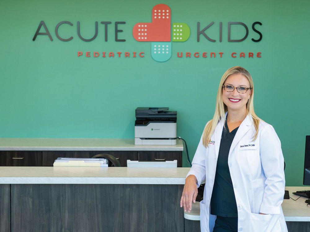 Chrysa standing at a reception desk wearing a white medical coat