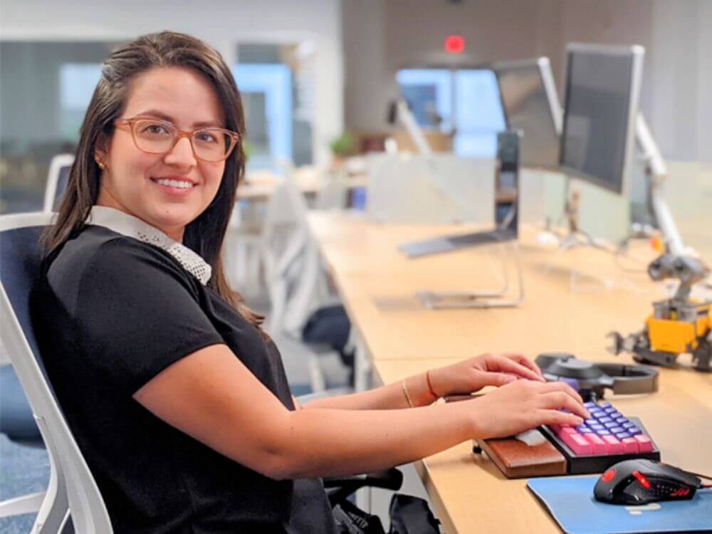 Melissa Royo typing on a keyboard, and turning to smile at the camera.