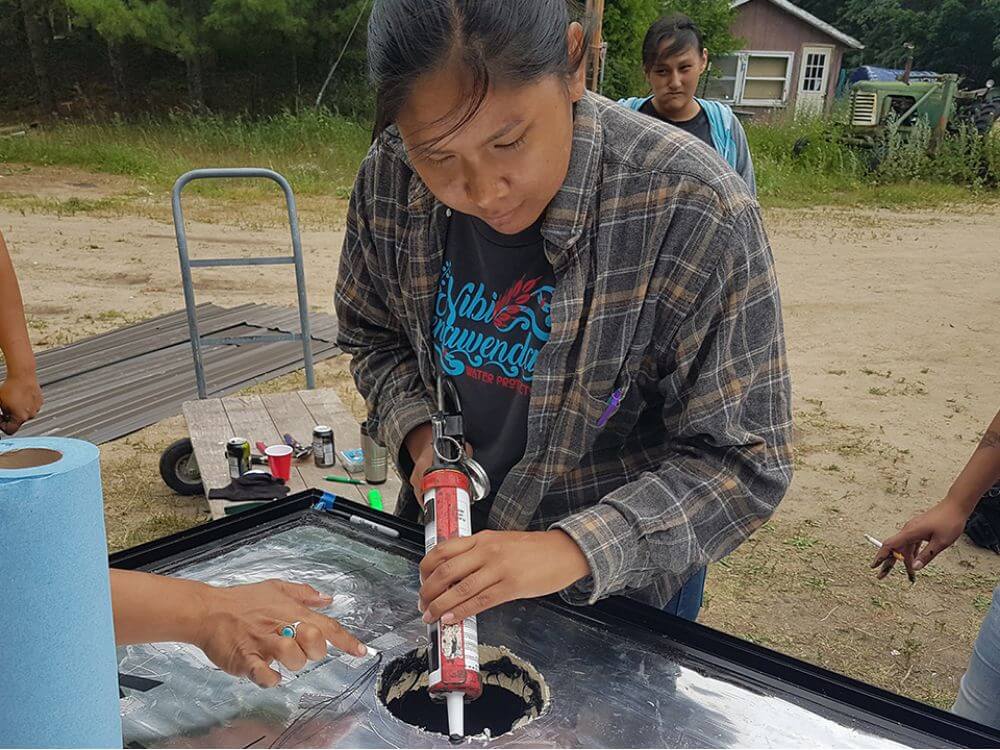 Sherralyn Sneezer works on a solar panel furnace in Minnesota she installed with the organization, Honor the Earth.