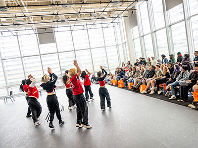 Students performing hip hop dance in front of a crowd.