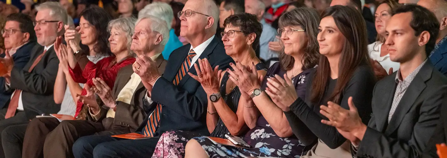 Audience members, including former R I T presidents, clap during an inauguration ceremony.