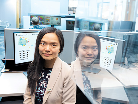 A female professor sitting at a computer, with a mirror image of her to the right.