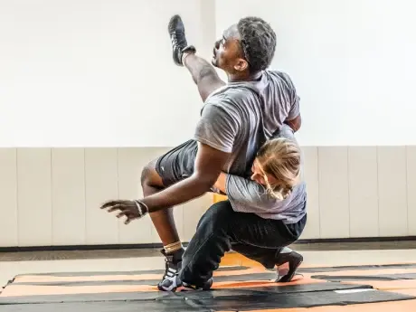 2 people wrestling on black and orange mats.