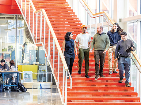 A group of 5 people walking down a set of bright orange stairs.