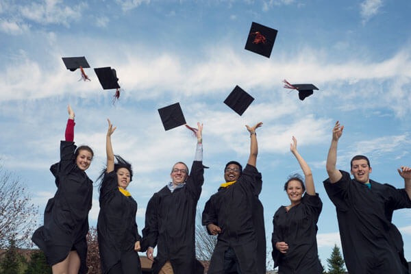 6 students tossing their caps in the air after they graduated
