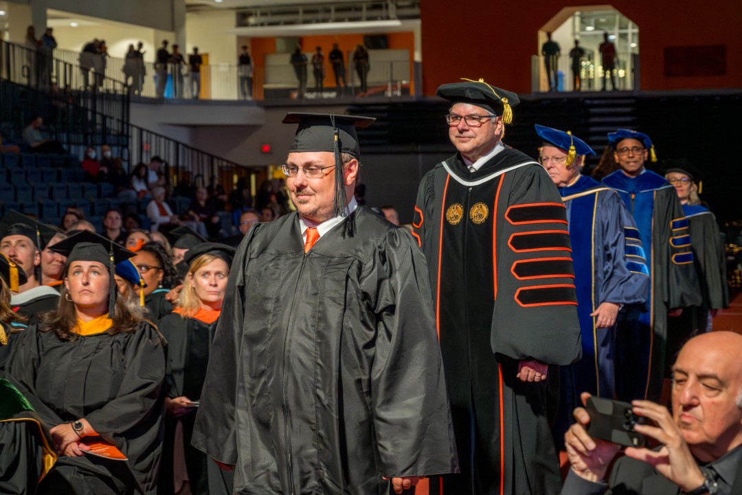 Faculty and administrators in academic robes process into the ceremony.
