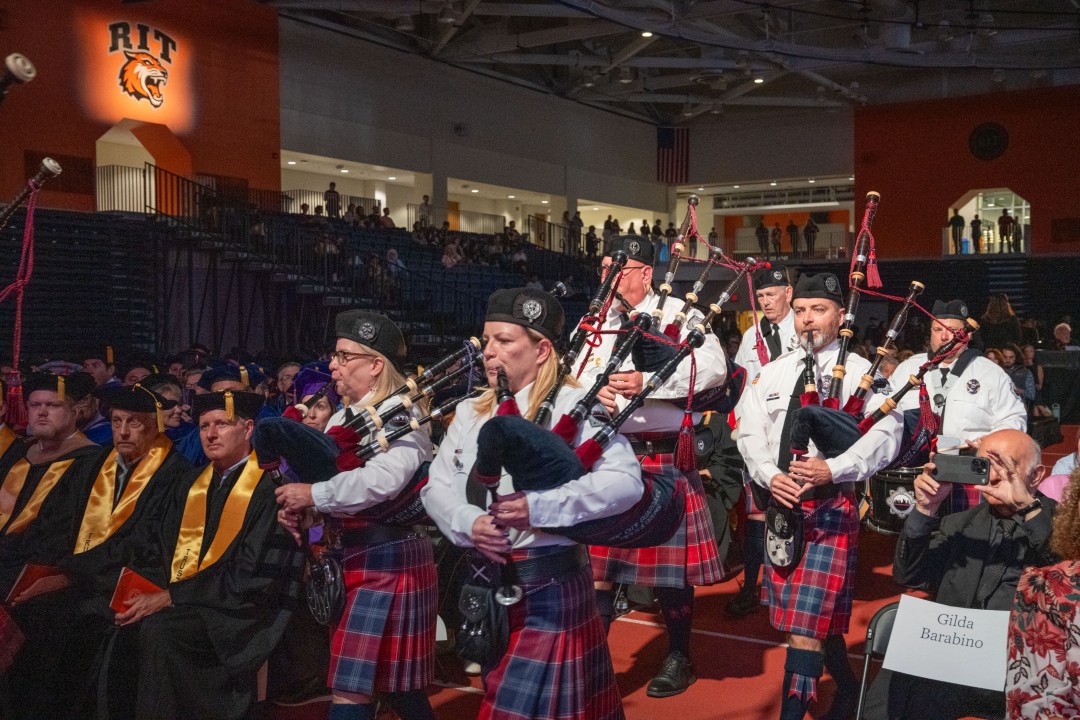 A bagpipe band in tartan kilts plays while marching down the aisle at the inauguration.