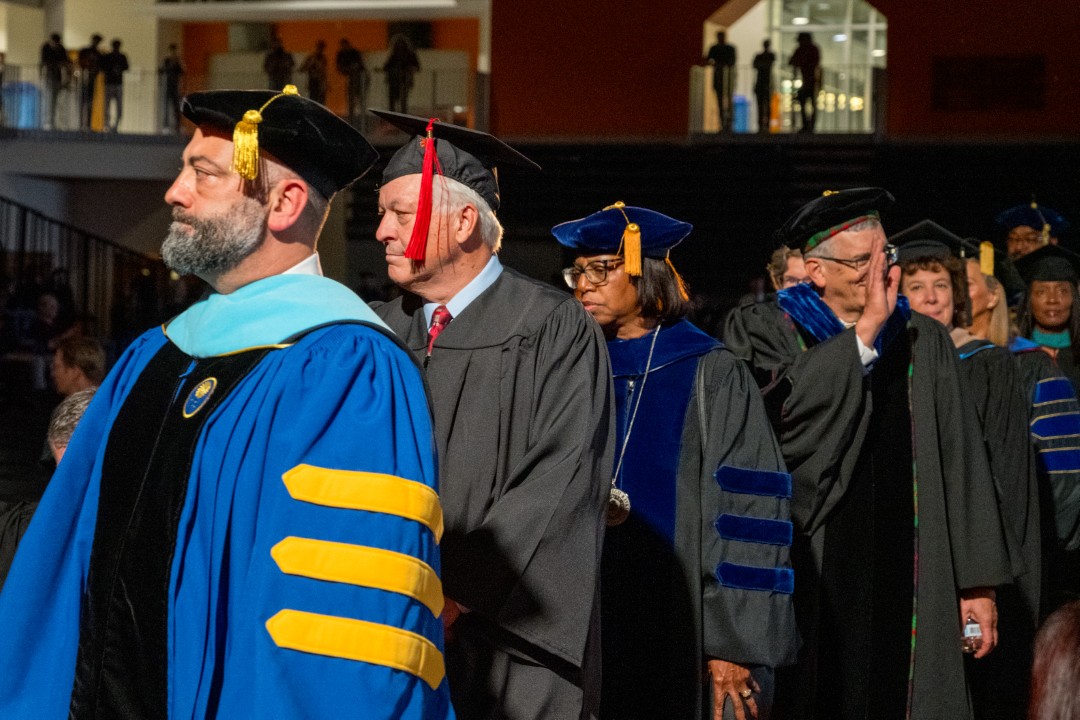 Faculty in academic regalia process into the ceremony.