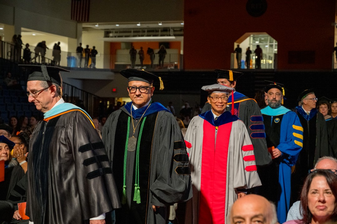 Faculty members in academic regalia walk in procession down the aisle at the inauguration.