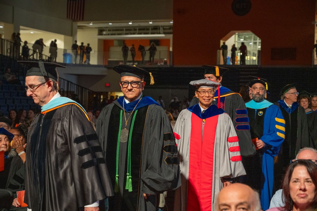 Faculty members in colorful academic robes process down the aisle during the ceremony.