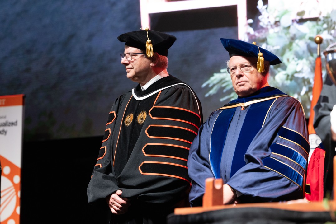 R I T President Sanders and a guest speaker in academic regalia stand on stage during the ceremony.