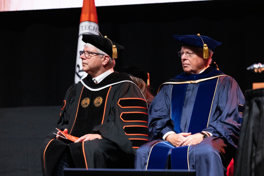R I T President Sanders and a guest speaker in academic regalia sit on stage during the ceremony.