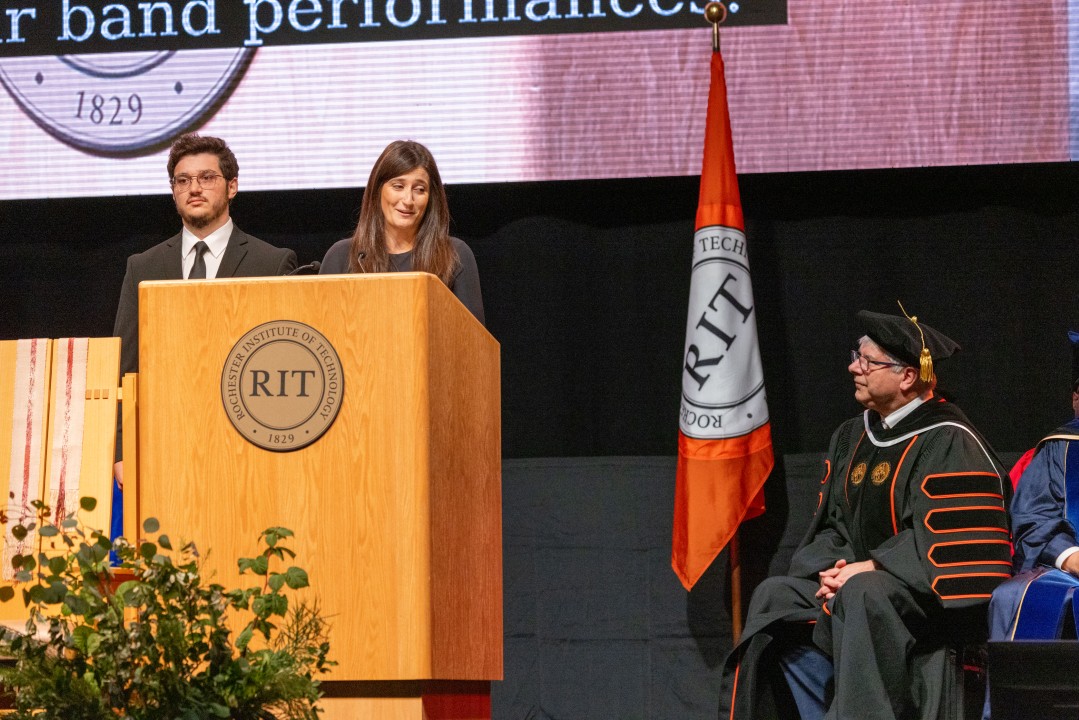 President Sanders's daughter and son speak at the podium while the president listens from a chair on stage.