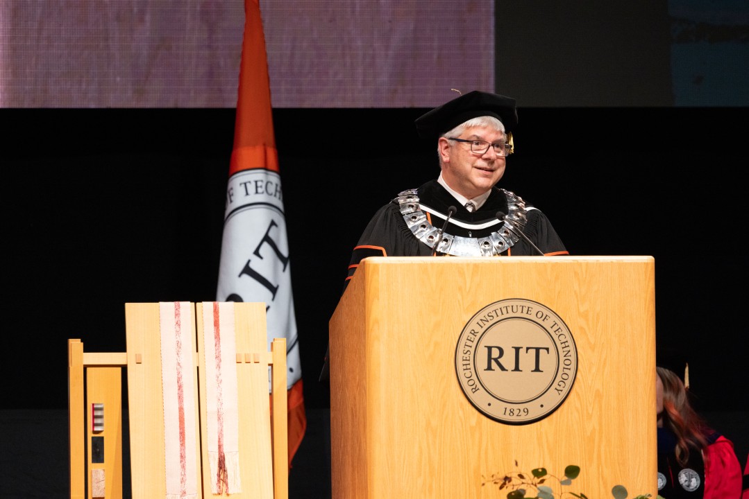 R I T Presideant Sanders in regalia speaks at the podium wearing the presidential medallion.
