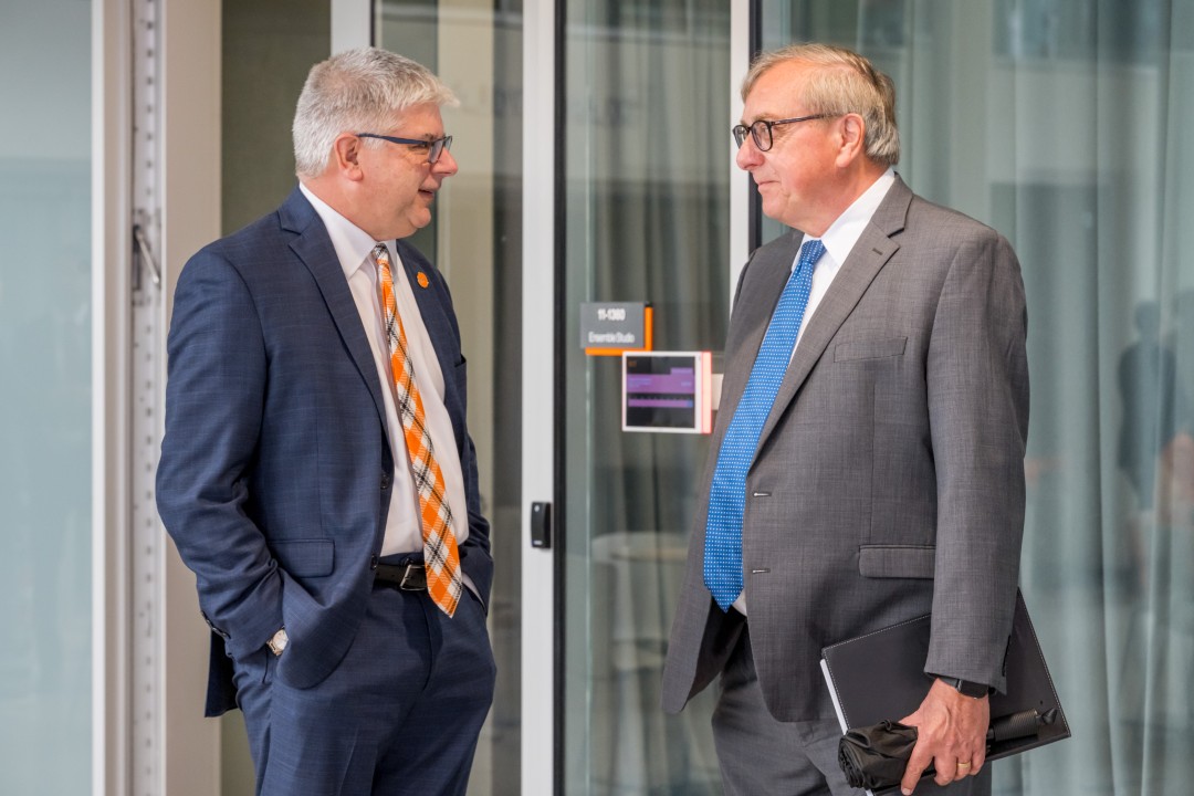 R I T president Sanders talks to another man.