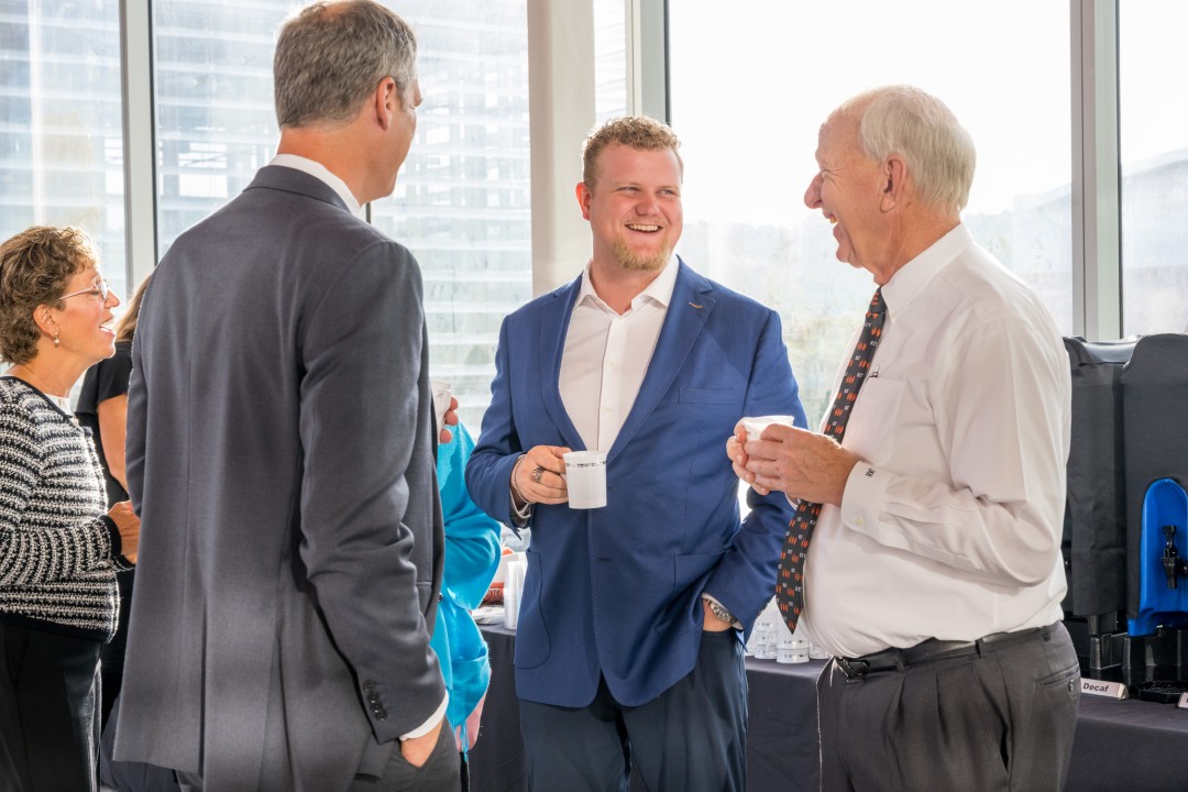 Three people smile and laugh at a reception.