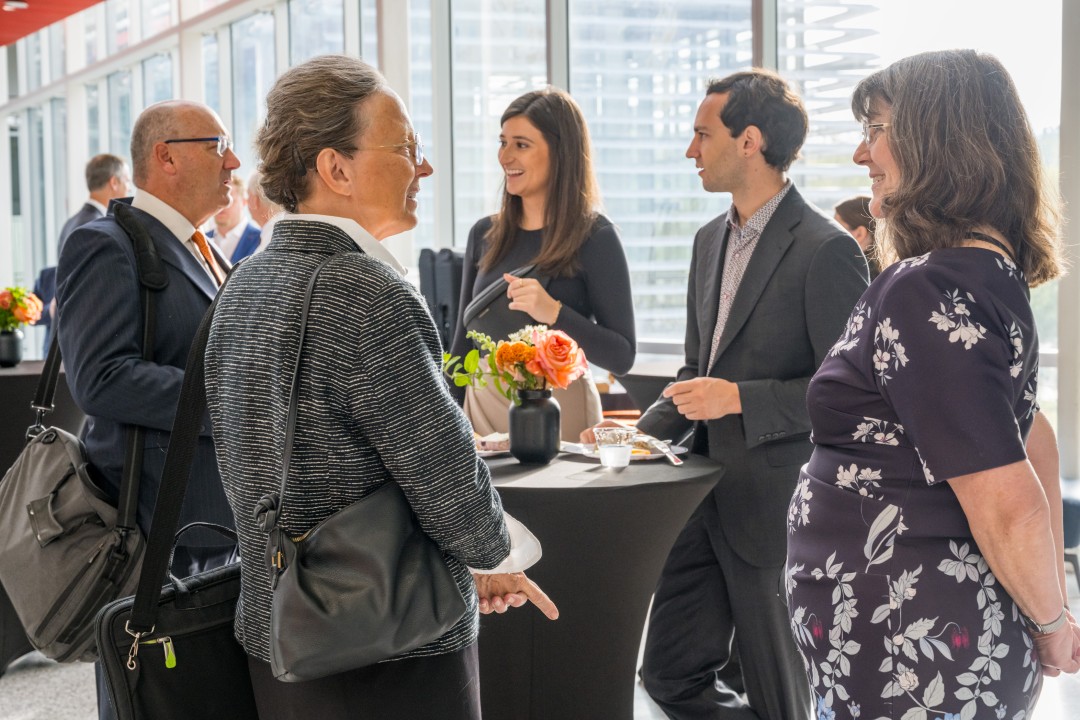 Five people standing and talking at a reception.