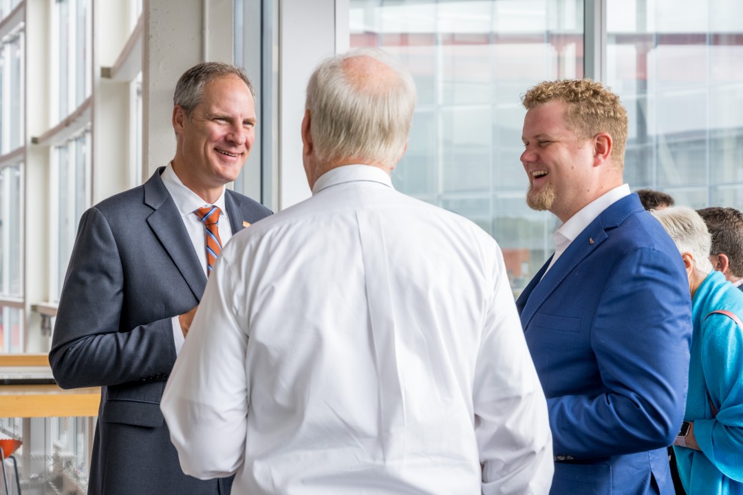 Three people smiling and talking at a reception.