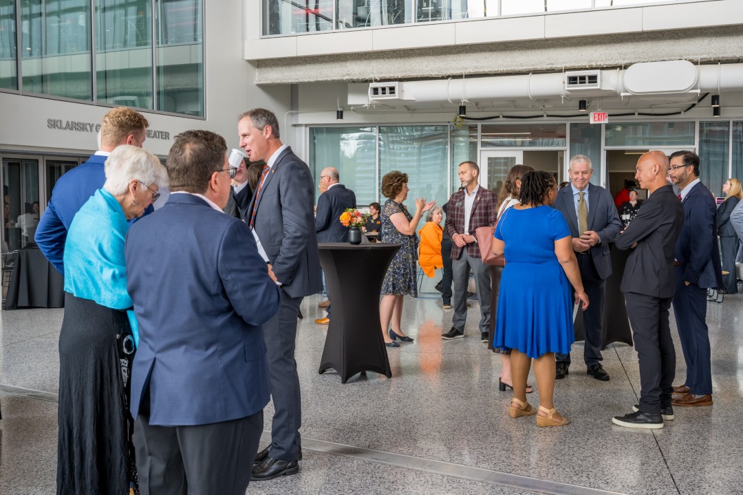 Several people standing in an atrium talking in small groups.