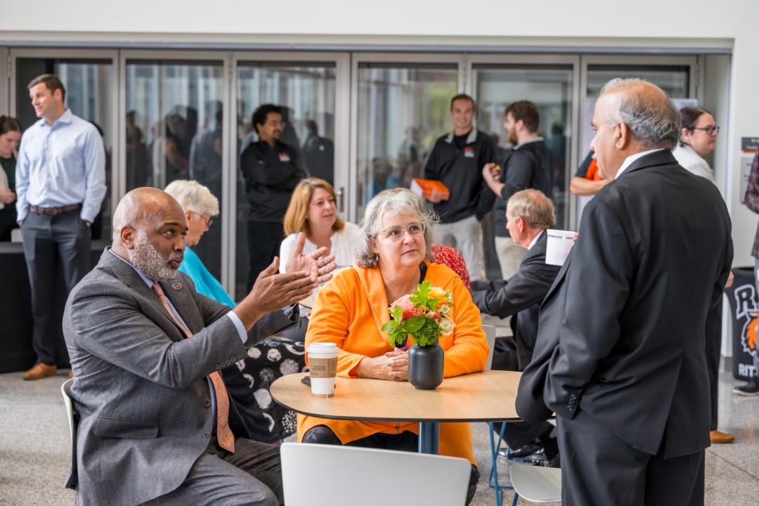 A speaker gestures while talking in a small group at a reception.