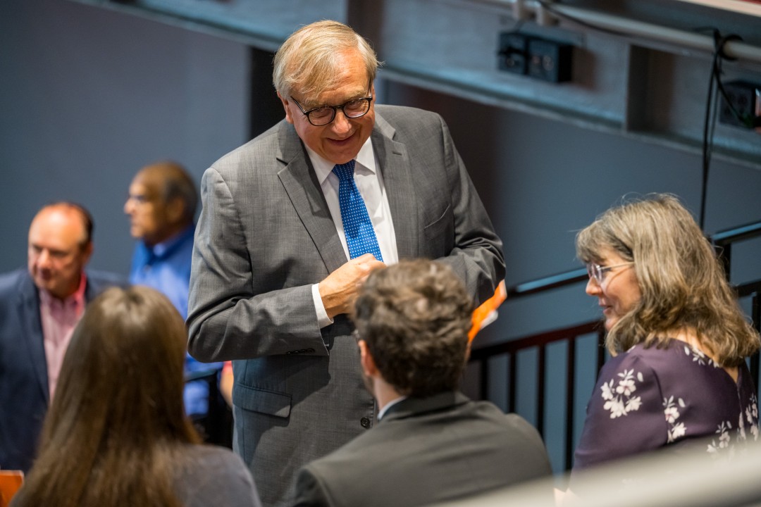 A man speakers to seated attendees at a panel discussion.