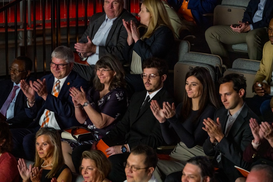 Audience members including R I T president Sanders and his family applaud during an event.