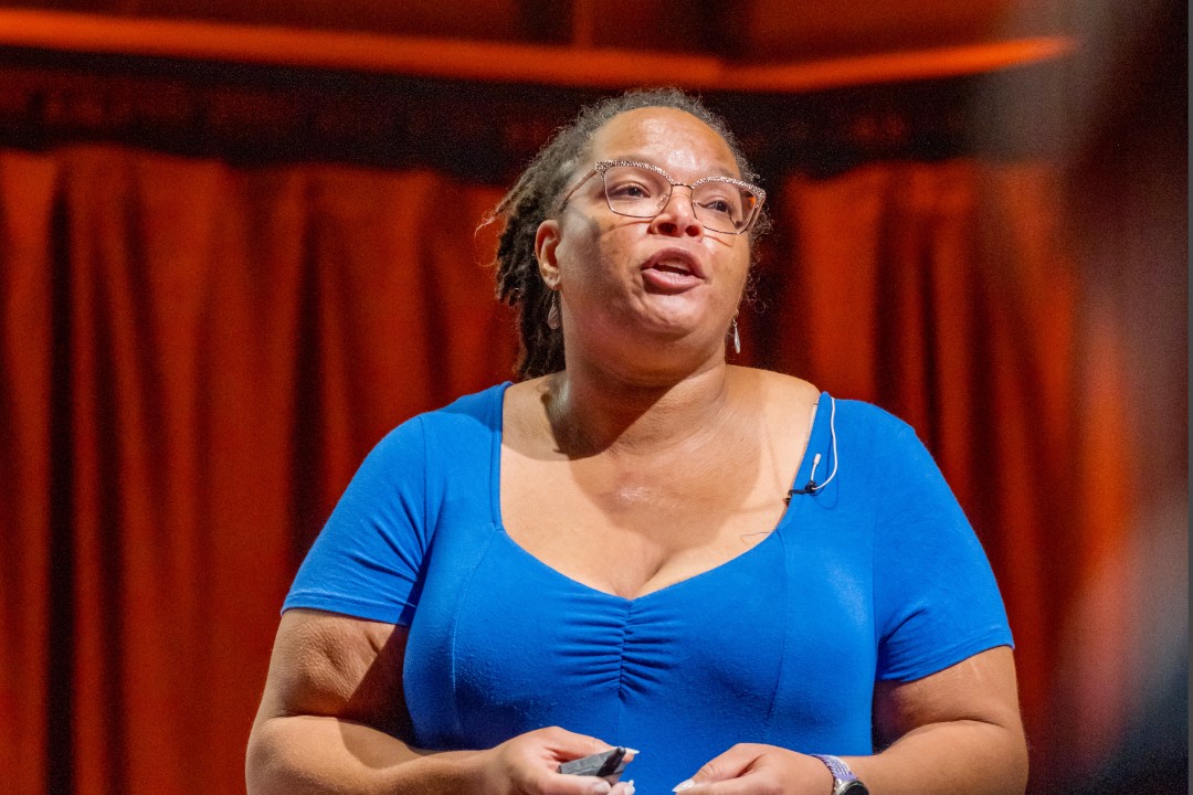 A woman in a blue top speaks at an event.