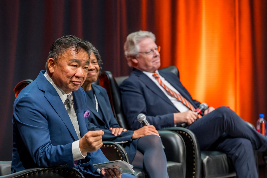 Three speakers seated on stage.