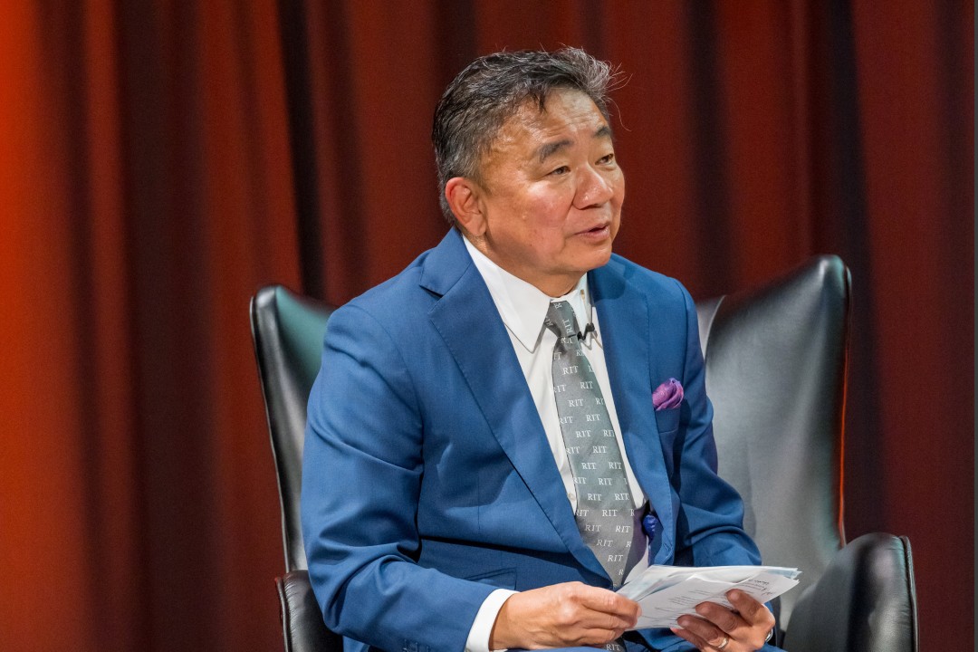 A seated man holding reference papers.