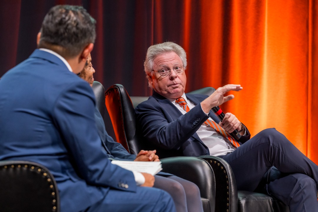 A panelist turns to the others as he speaks.