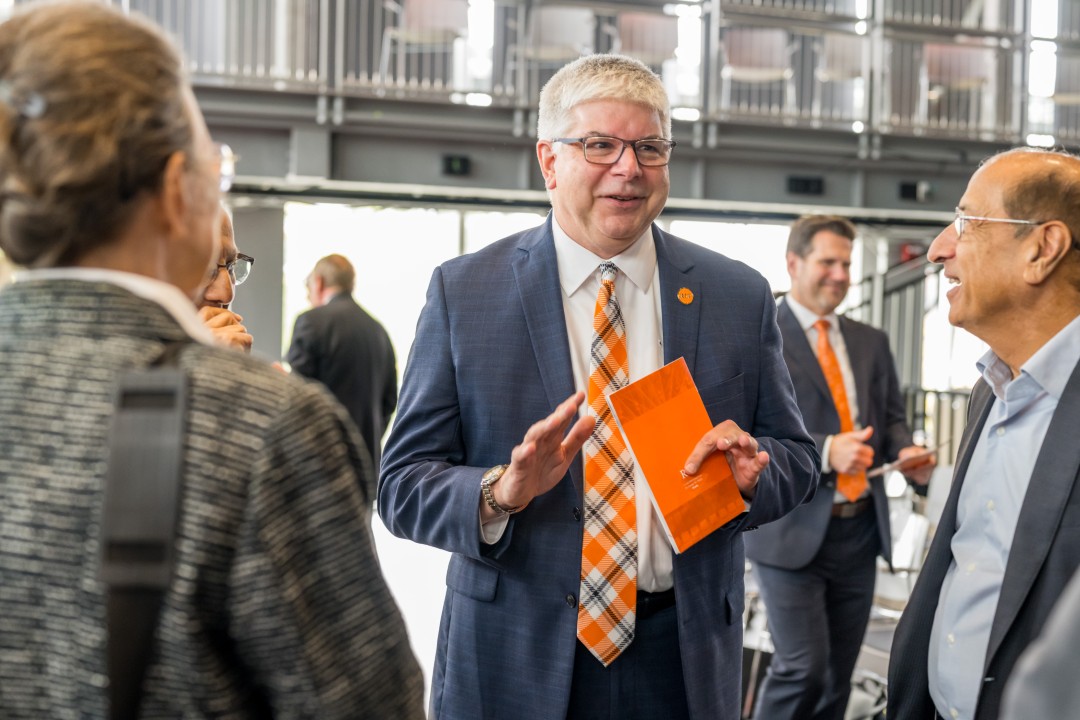 R I T president Sanders smiles and talks to a small crowd.