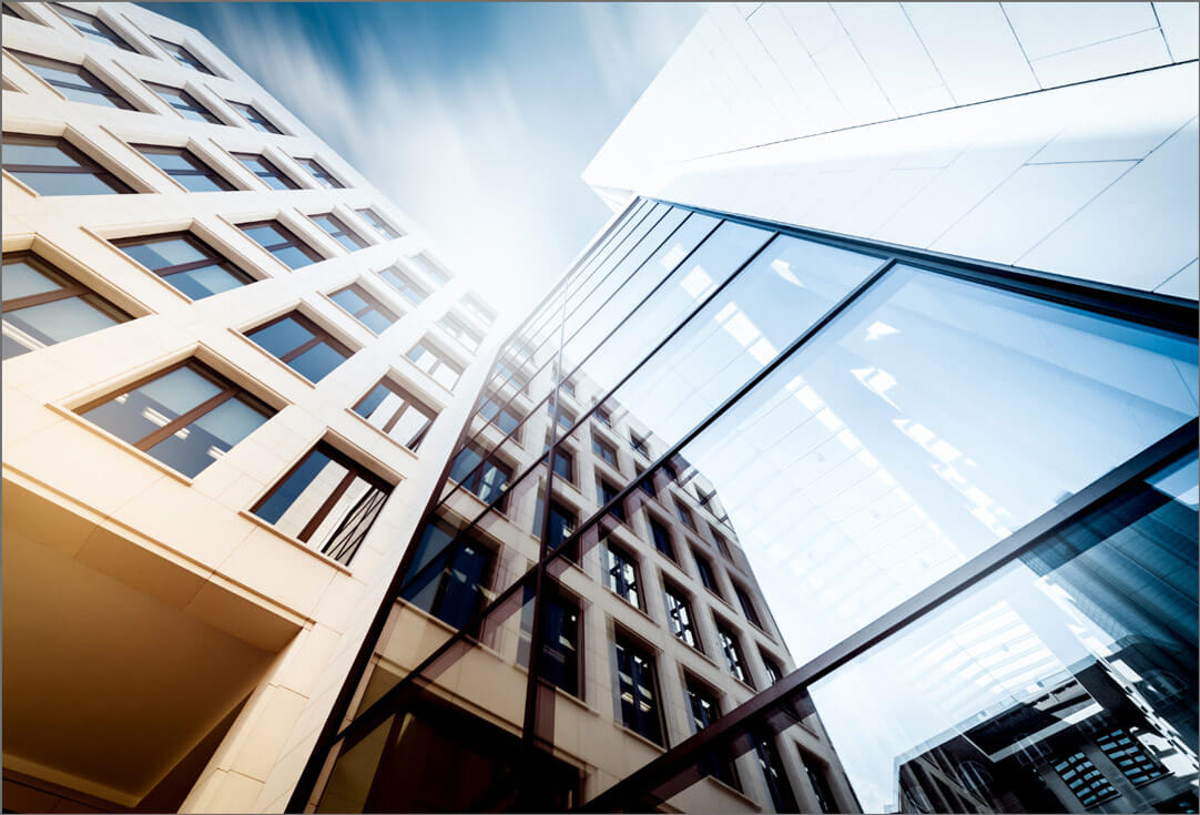The exterior of an L-shaped building with a glass wall on the right and many windows on the left