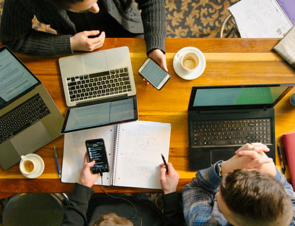 An overhead view of two students using their computers and notebooks.