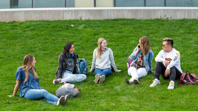 Five students sitting on the lawn outside of the Innovation Center.