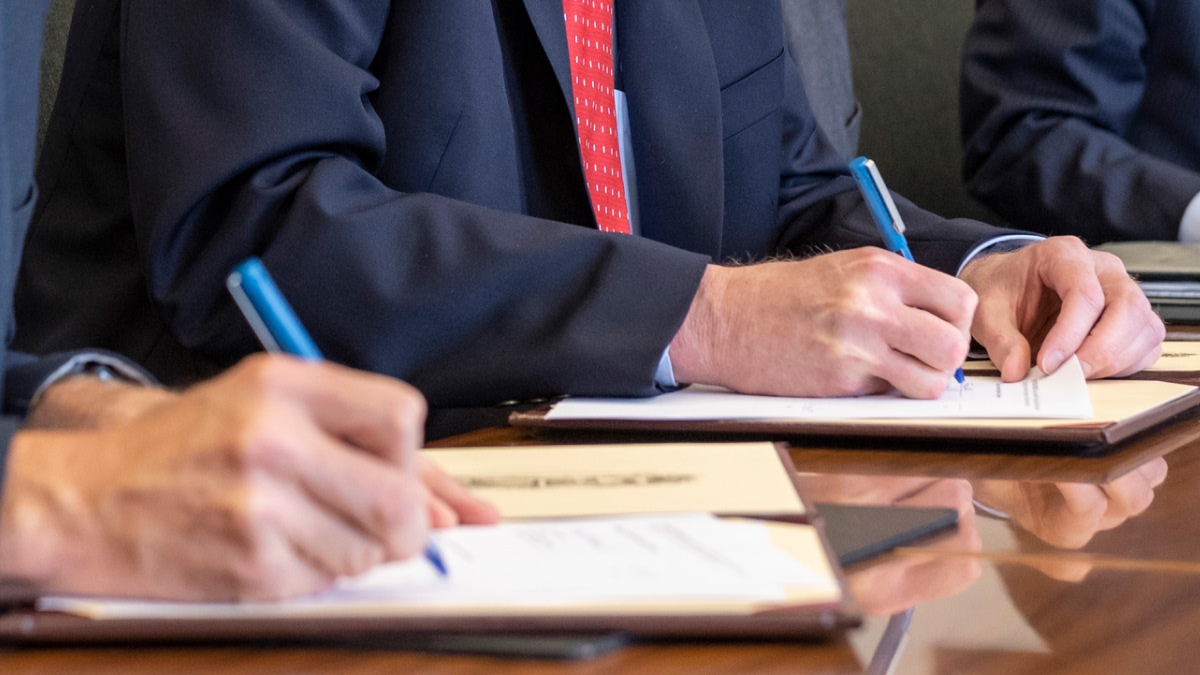 Closeup of officials signing documents.