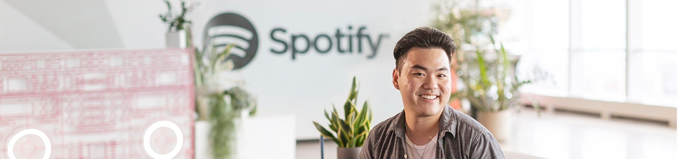Man posing in front of a spotify sign with plants