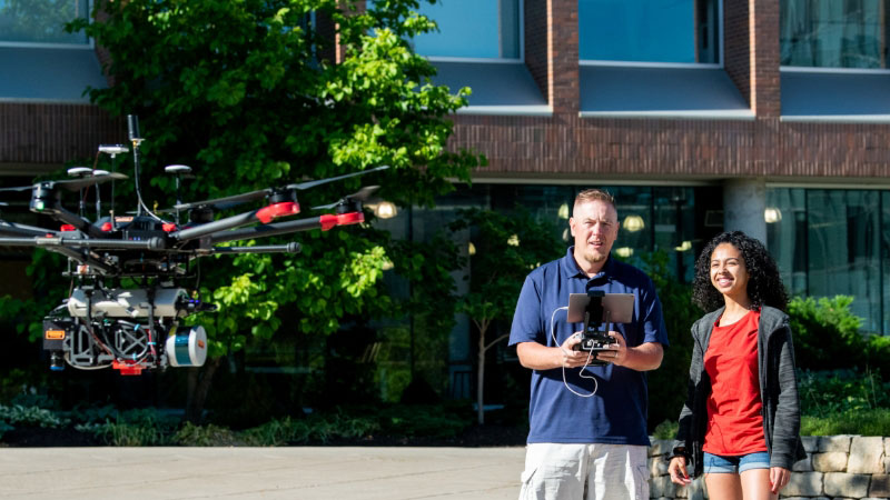 An R I T professor and student flying a drone.