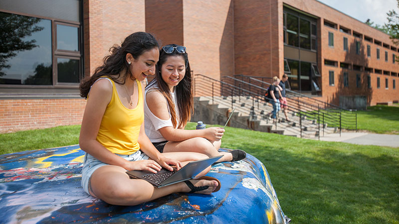 students outside sitting on a painted rock